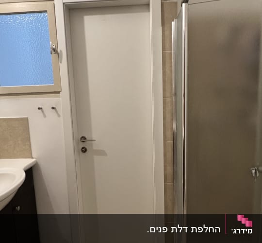 דלת לבנה בחדר אמבטיה עם כיור ומקלחון